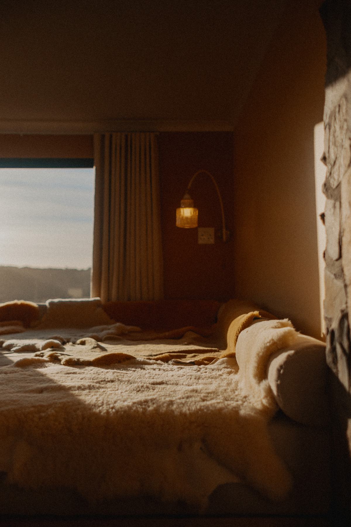 Late light across a sheepskin-covered bed at Nima Lodge