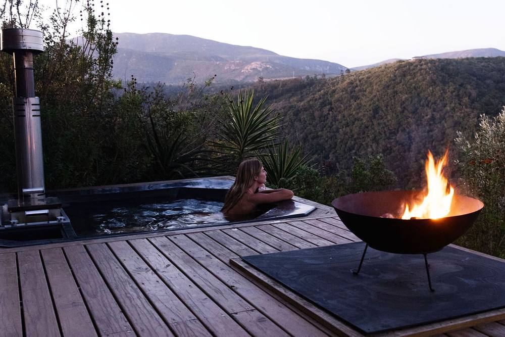 Wood-fired hot tub and fire pit at dusk