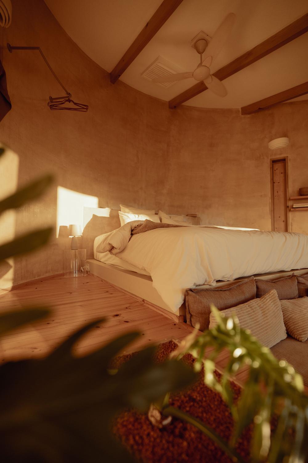 Bed on its platform, curved plaster walls
