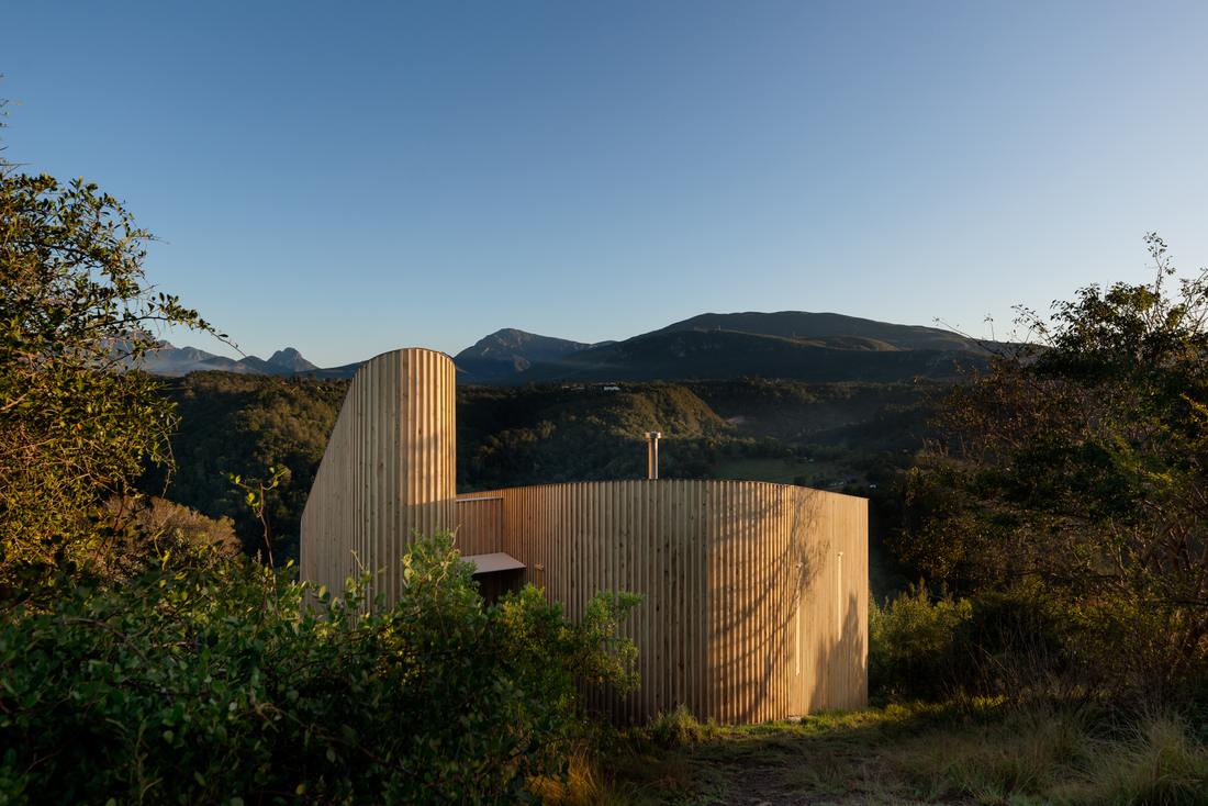 Curved timber cladding against the mountains