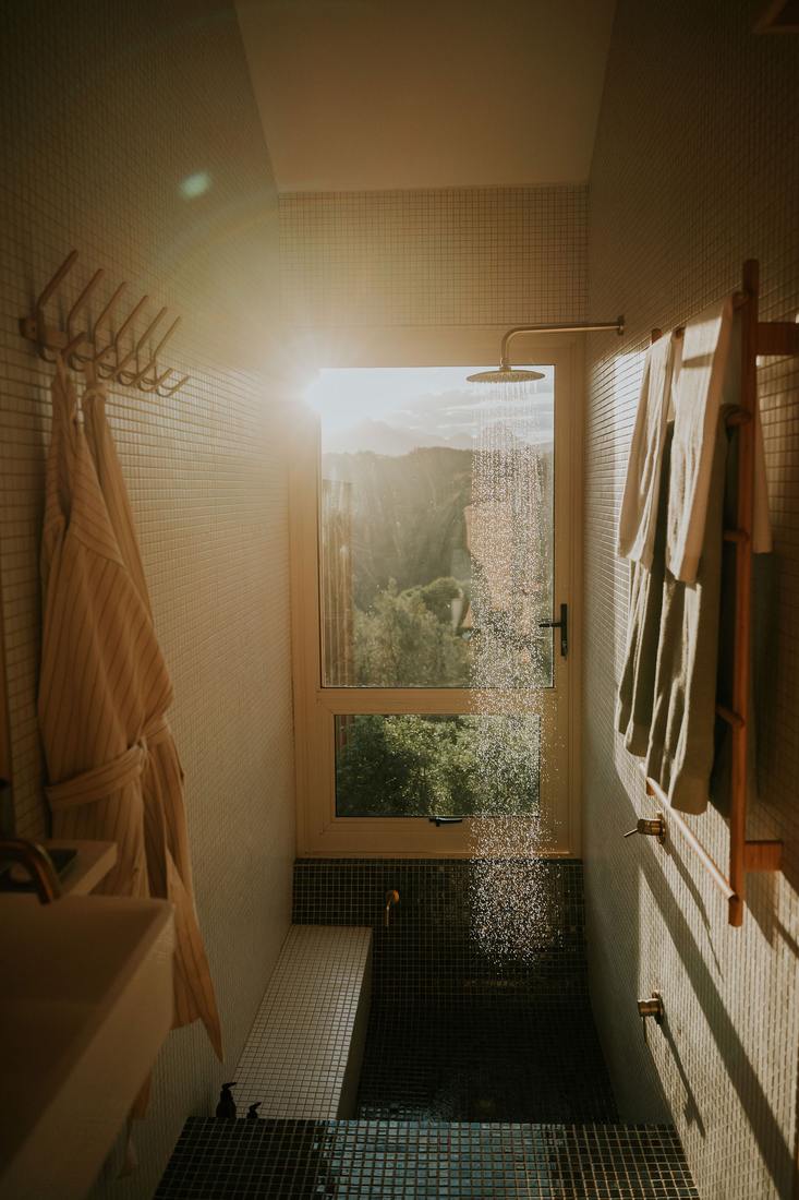 Rain shower in the tiled bathroom at sunset