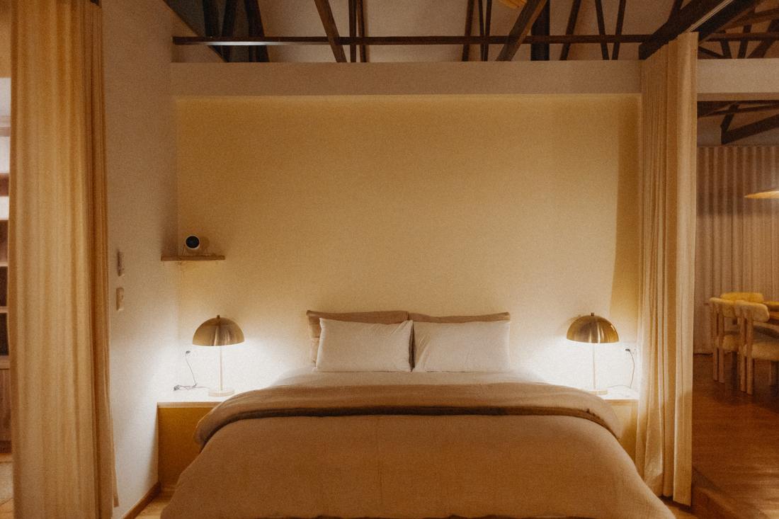 Bed between brass lamps under the trusses